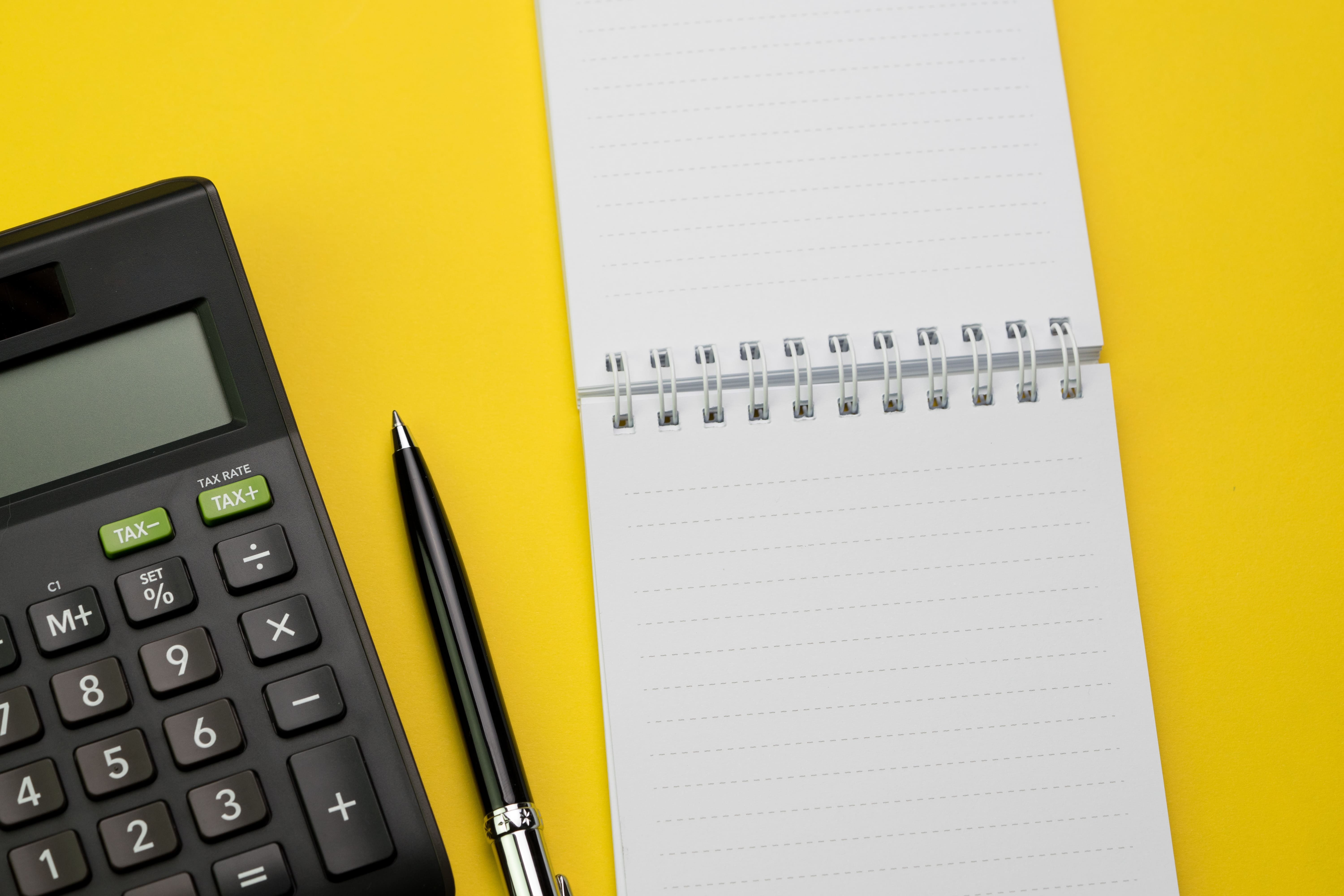 calculatrice cahier et stylo sur fond jaune