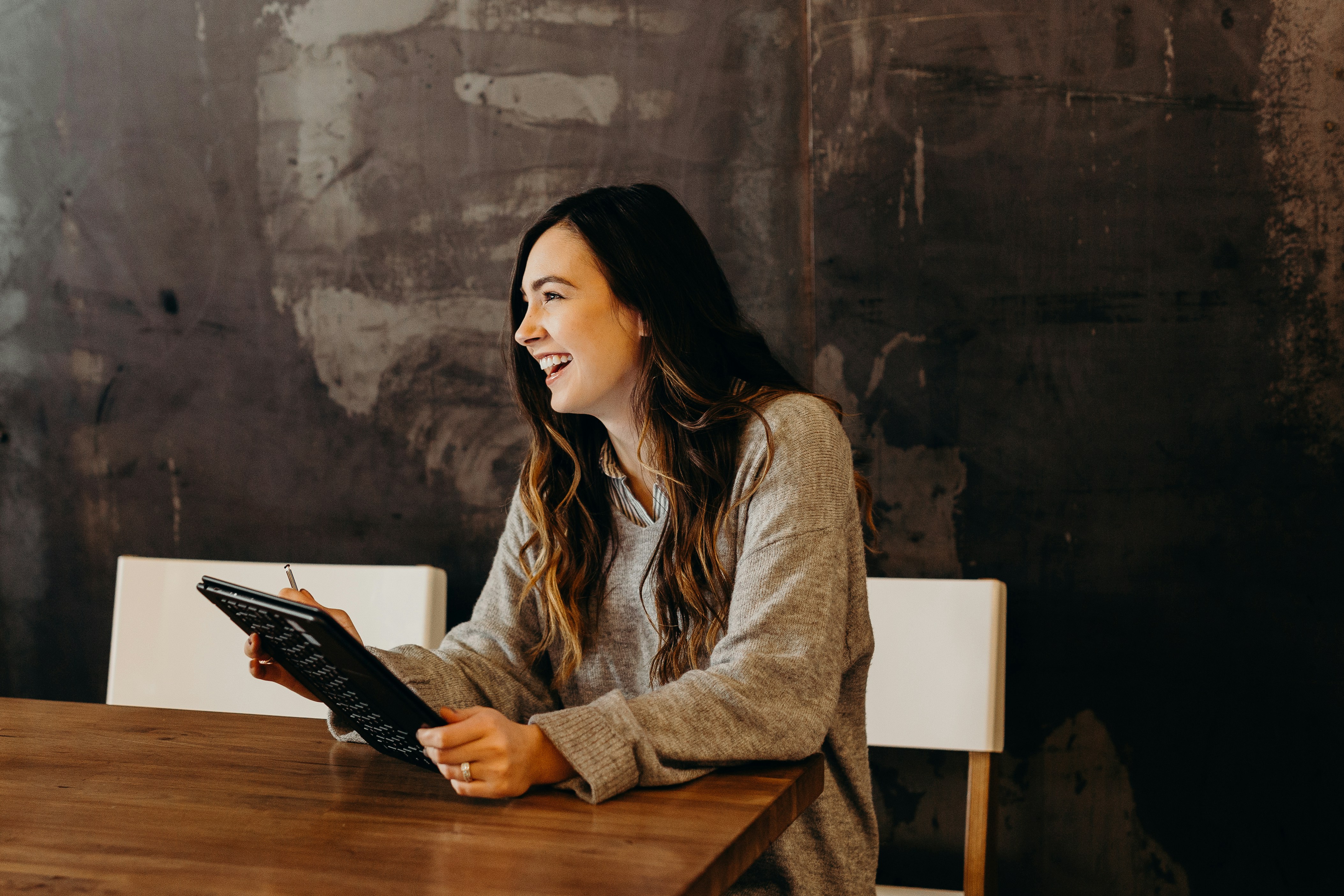 Cette image représente une femme souriant en tenant sa tablette